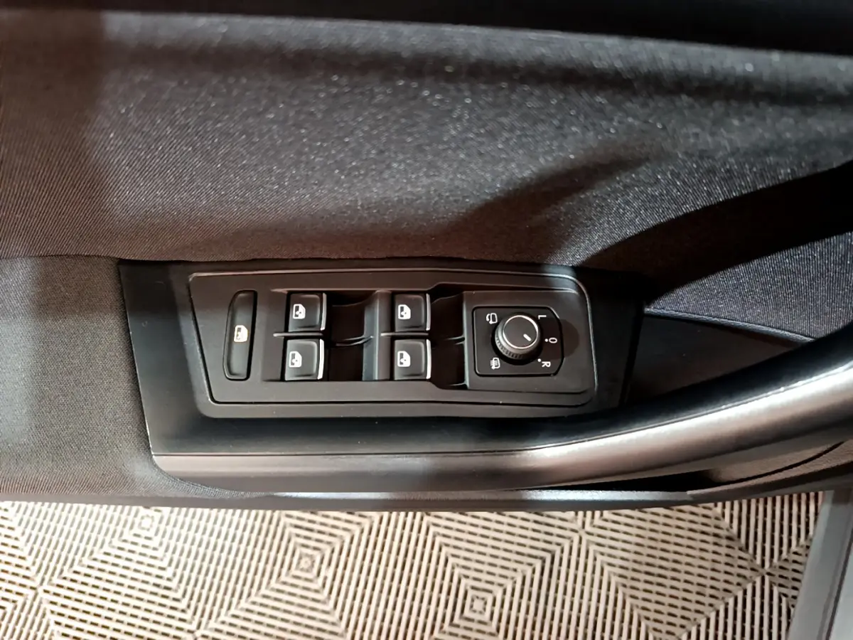 Détail des commandes des vitres et rétroviseurs côté conducteur du Volkswagen T-Roc gris foncé.