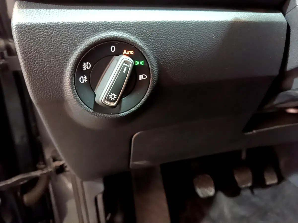 Gros plan sur la commande des phares du Volkswagen T-Roc 1.0 TSI 110 Lounge, intérieur noir.