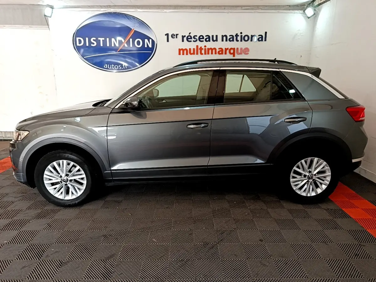 Profil droit d'un Volkswagen T-Roc gris foncé 2021, finition Lounge, avec jantes alliage et rails de toit noirs.