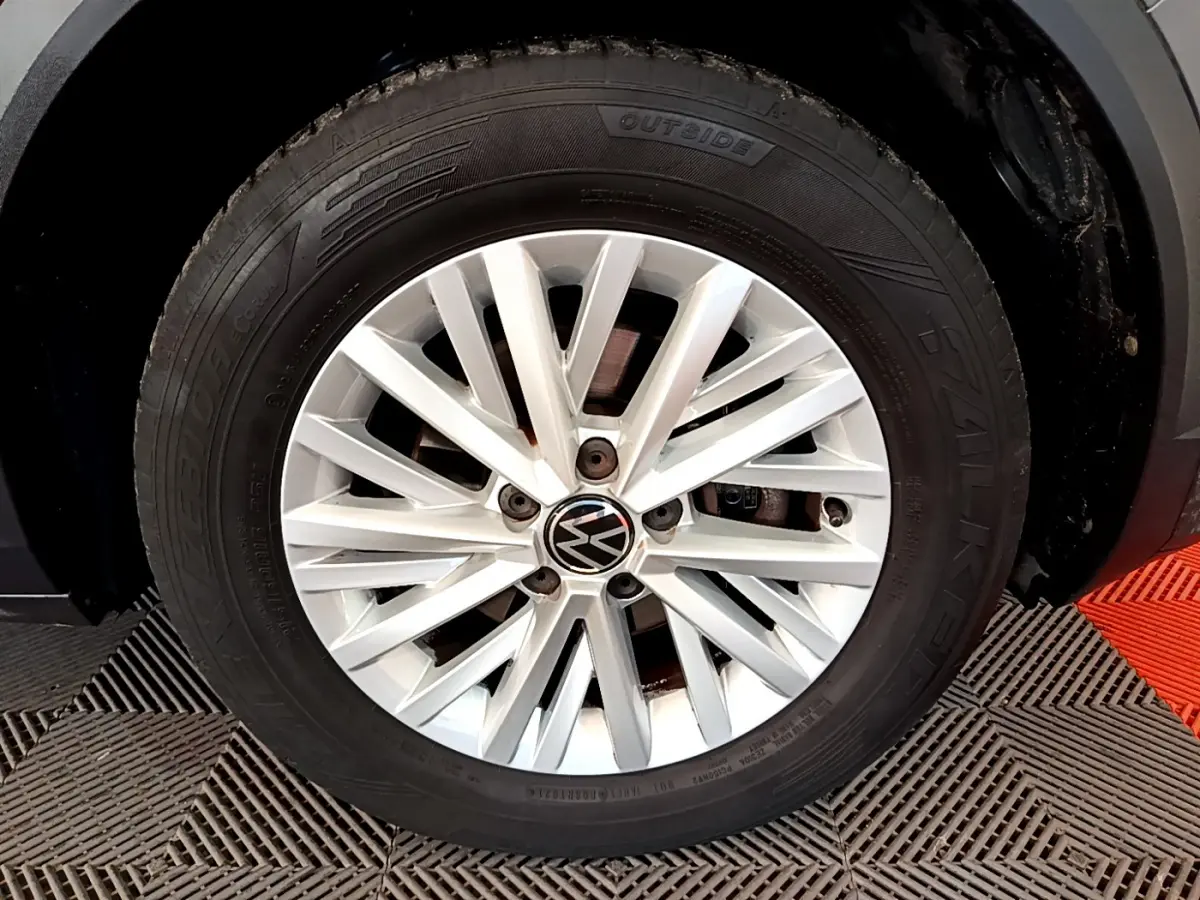 Gros plan sur la jante alliage argentée avec logo Volkswagen, montée sur un pneu Falken d’un Volkswagen T-Roc gris foncé.
