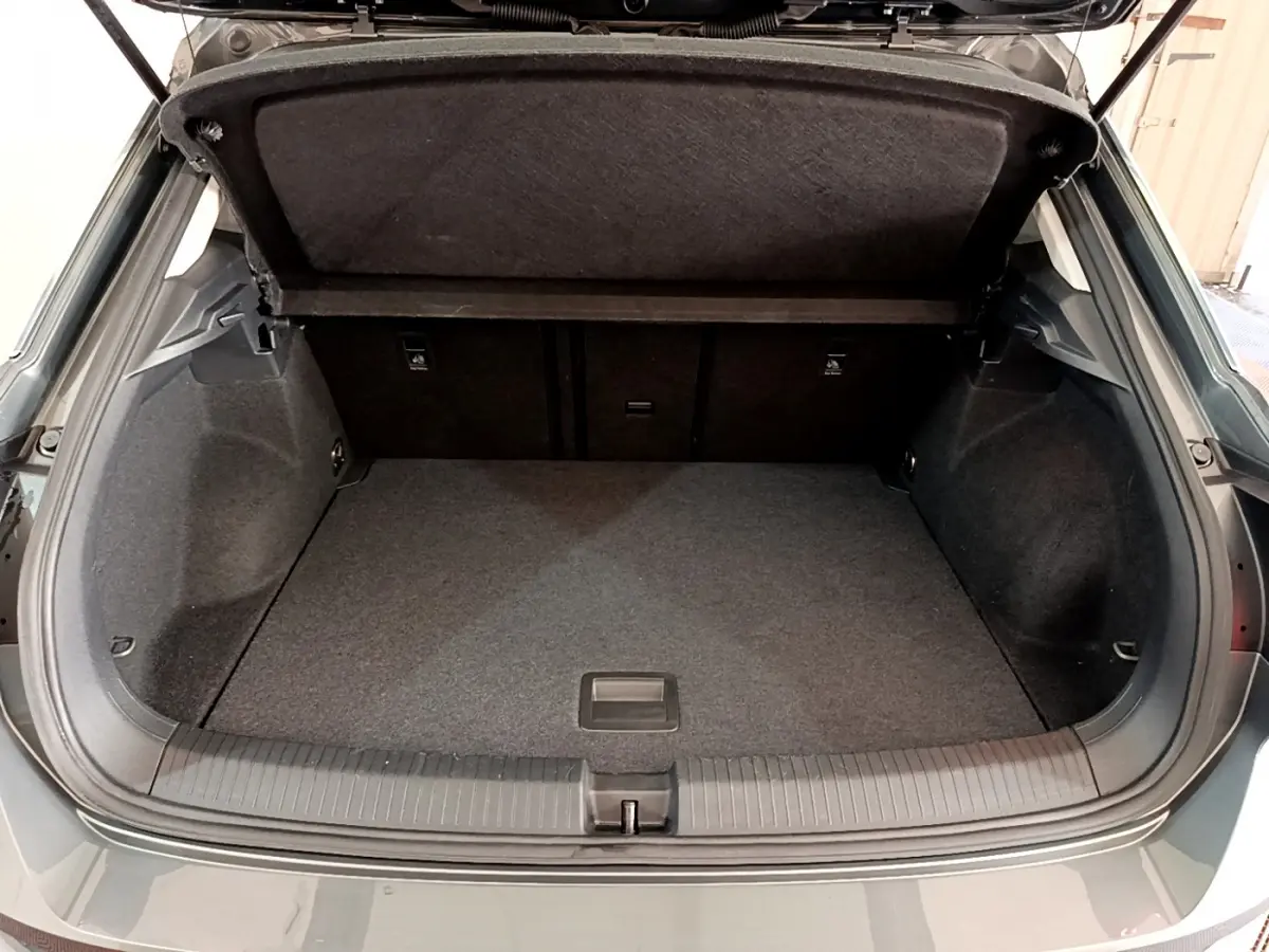 Coffre ouvert vu de l'arrière d'un Volkswagen T-Roc gris foncé, montrant l'espace de chargement vide et la tablette de séparation.