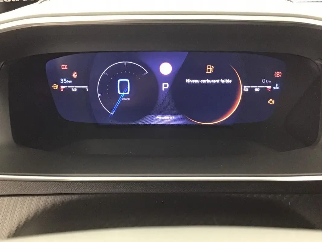 Tableau de bord numérique de la Peugeot 2008 Hybrid 145ch GT, affichant vitesse à 0 km/h et alerte niveau carburant faible.