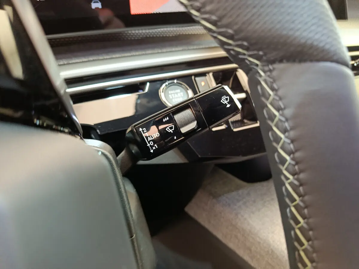 Gros plan sur la manette d'essuie-glace à gauche du volant cuir du Peugeot 3008 noir, avec bouton démarrage visible.