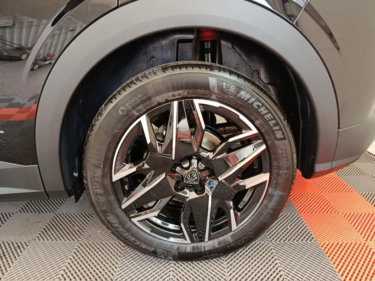 Gros plan sur la roue avant droite noire du Peugeot 3008 1.2 HYBRID 145 E-DCS6 GT avec jante alliage stylisée.