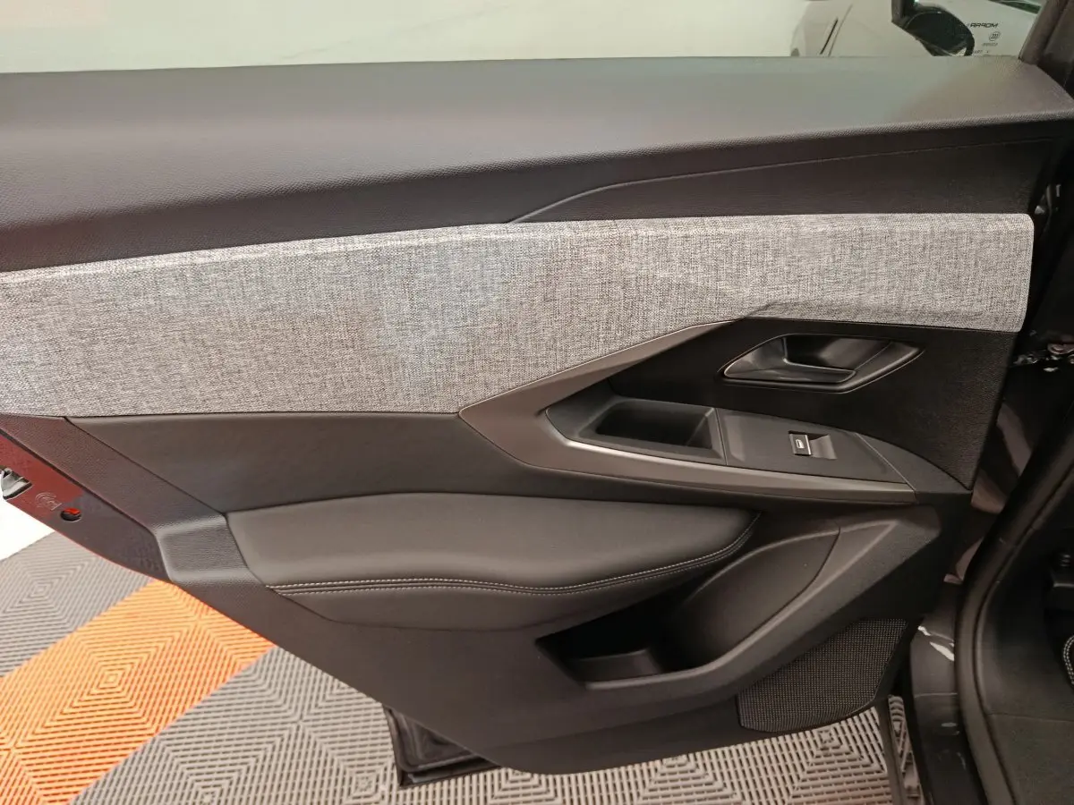 Panneau de porte côté gauche du Peugeot 3008 noir 2025 avec insert tissu gris et commandes électriques.