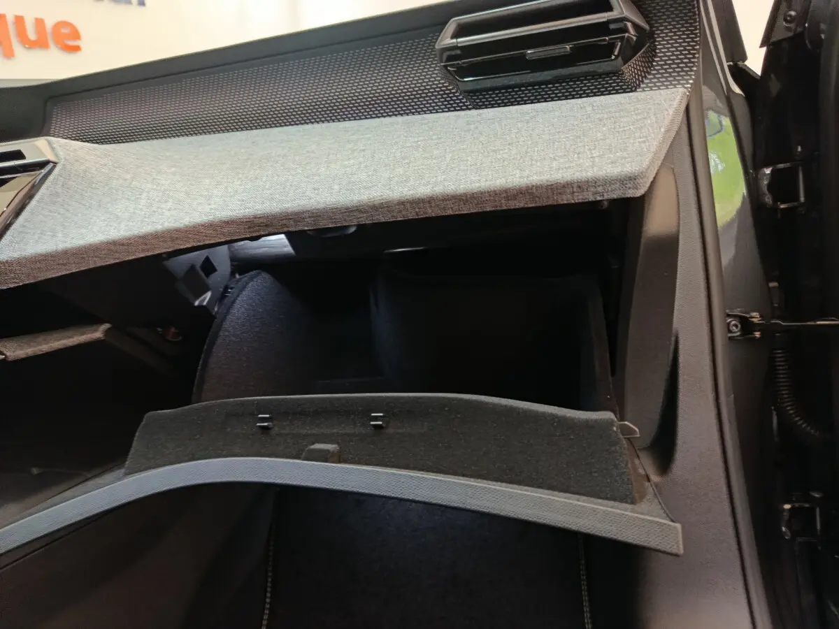 Intérieur du Peugeot 3008 noir 2025 montrant la boîte à gants ouverte sous le tableau de bord gris clair.