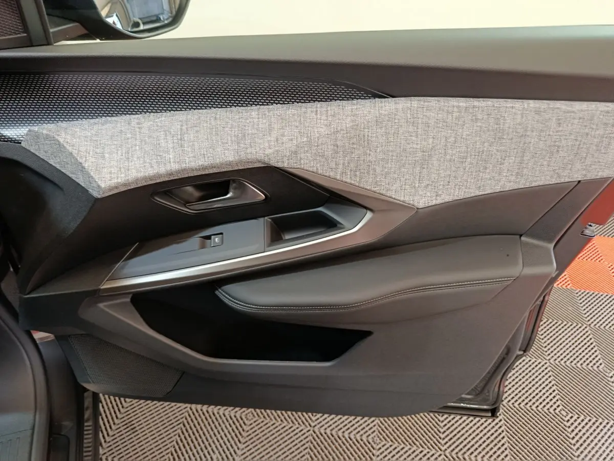 Porte intérieure côté gauche du Peugeot 3008 2025 en noir, avec habillage tissu gris et garniture cuir noire.