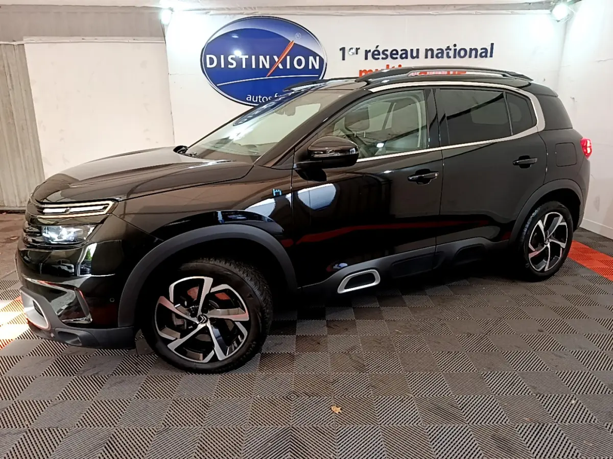 Vue 3/4 avant droit du Citroën C5 Aircross Hybrid noir avec jantes alliage et barres de toit chromées.