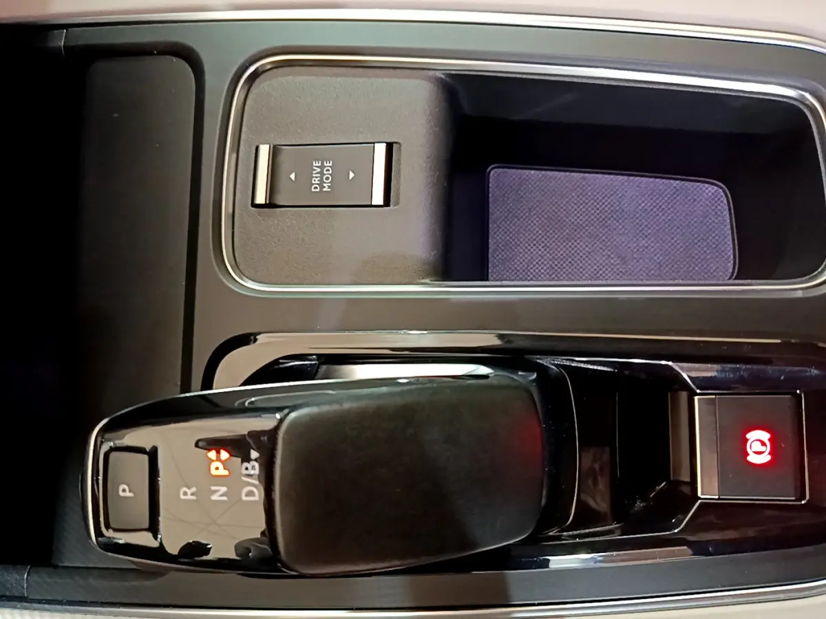 Gros plan sur la console centrale noire du Citroën C5 Aircross Hybrid avec levier de vitesses automatique et bouton frein à main électrique allumé.