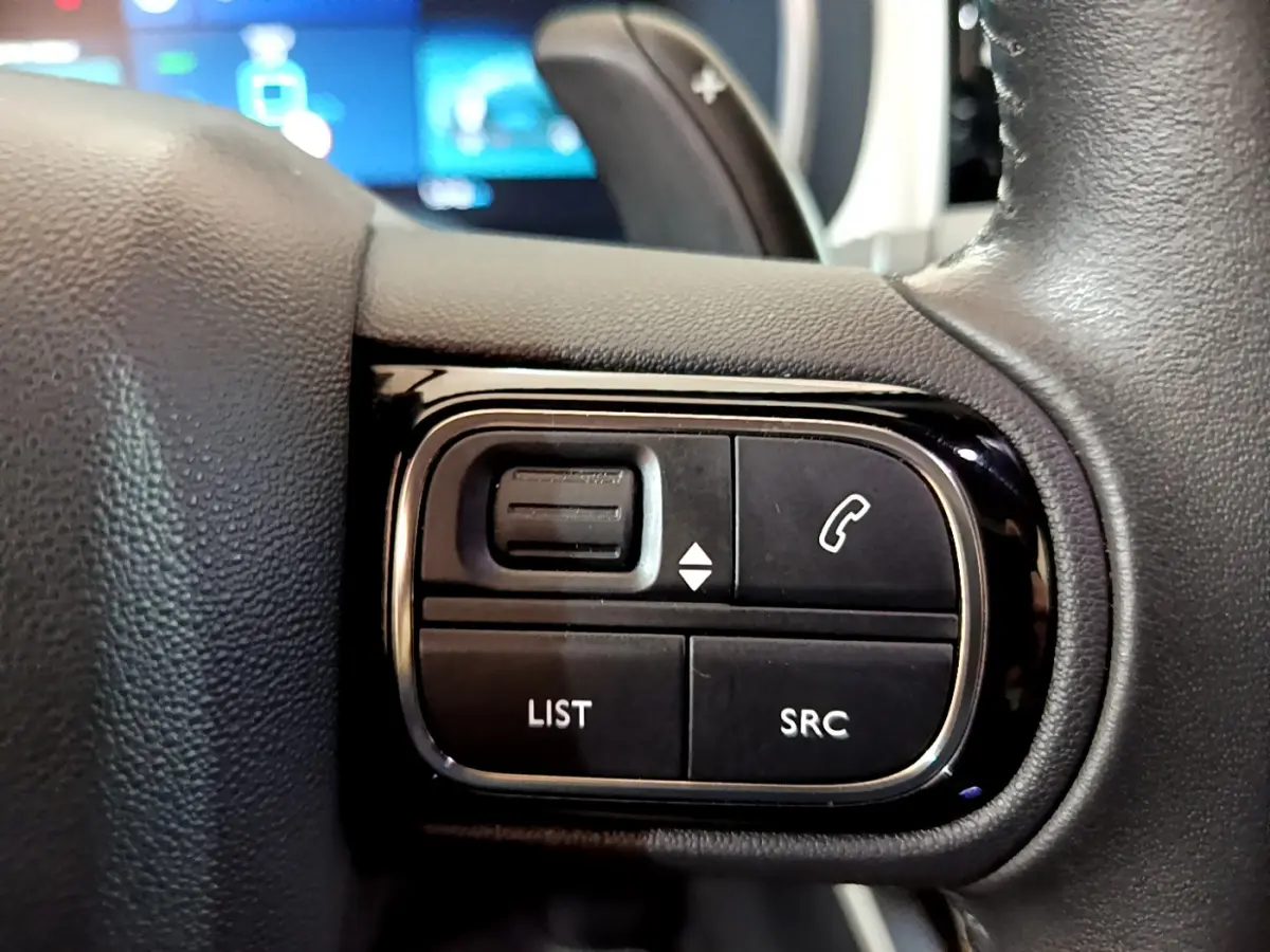 Gros plan sur les commandes gauche du volant cuir noir du Citroën C5 Aircross Hybrid 225 ë-EAT8 Shine, boutons multifonctions.