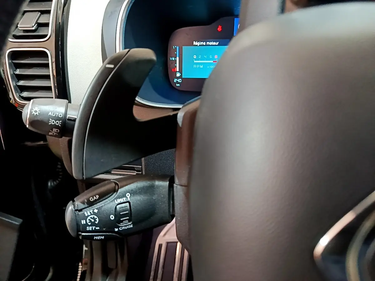Gros plan sur le volant et les commandes au volant du Citroën C5 Aircross Hybrid noir, avec affichage numérique du régime moteur.