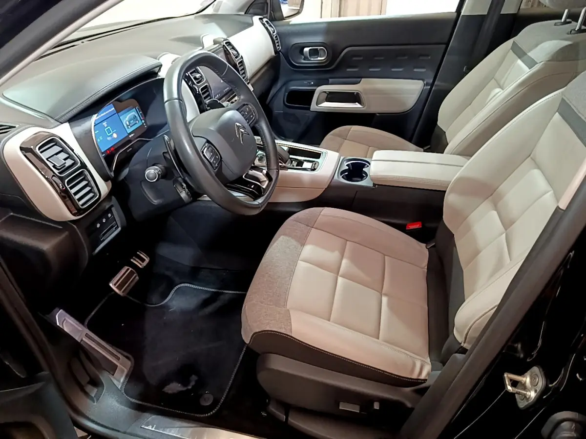 Vue intérieure côté conducteur du Citroën C5 Aircross Hybrid noir, sièges bicolores beige et gris, tableau de bord digital.