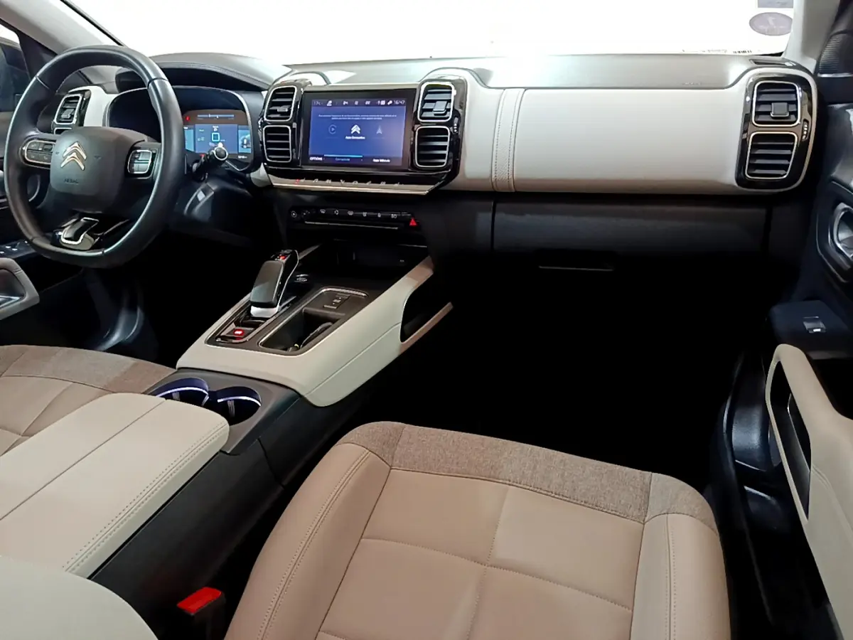 Vue intérieure côté conducteur du Citroën C5 Aircross Hybrid 225 avec tableau de bord beige et écran tactile central.