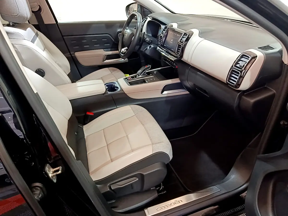 Intérieur avant du Citroën C5 Aircross Hybrid noir, sièges bicolores beige et gris, tableau de bord moderne avec écran tactile.