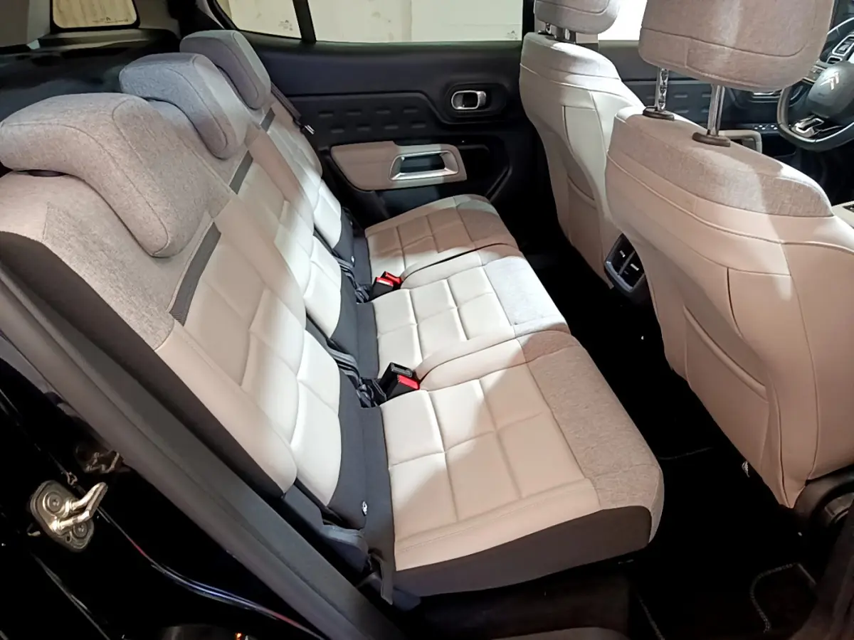 Vue intérieure côté gauche des sièges arrière bicolores beige et gris du Citroën C5 Aircross Hybrid 225 ë-EAT8 Shine noir.