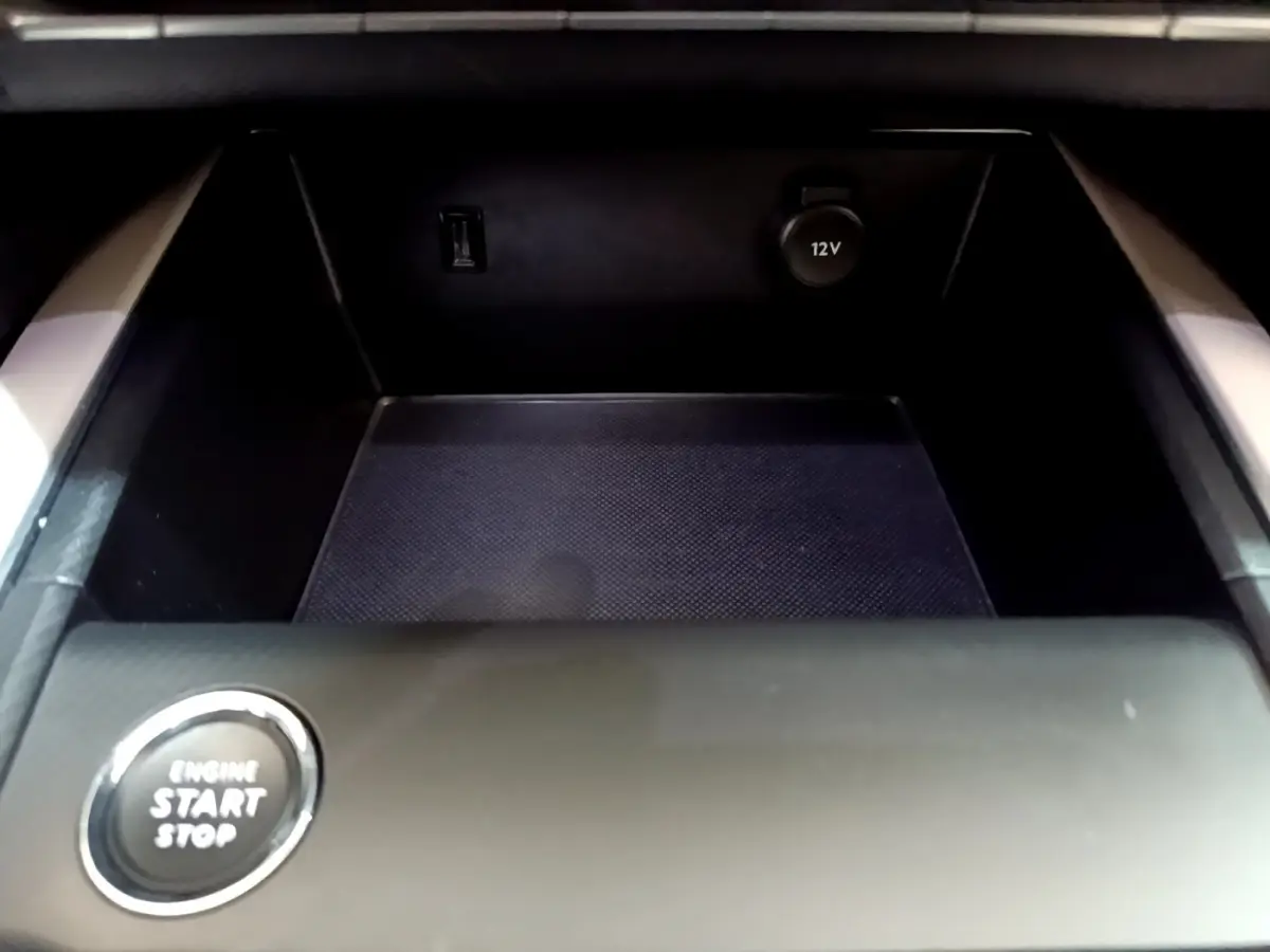 Gros plan sur la console centrale noire du Citroën C5 Aircross Hybrid avec bouton start/stop et prise 12V visible.