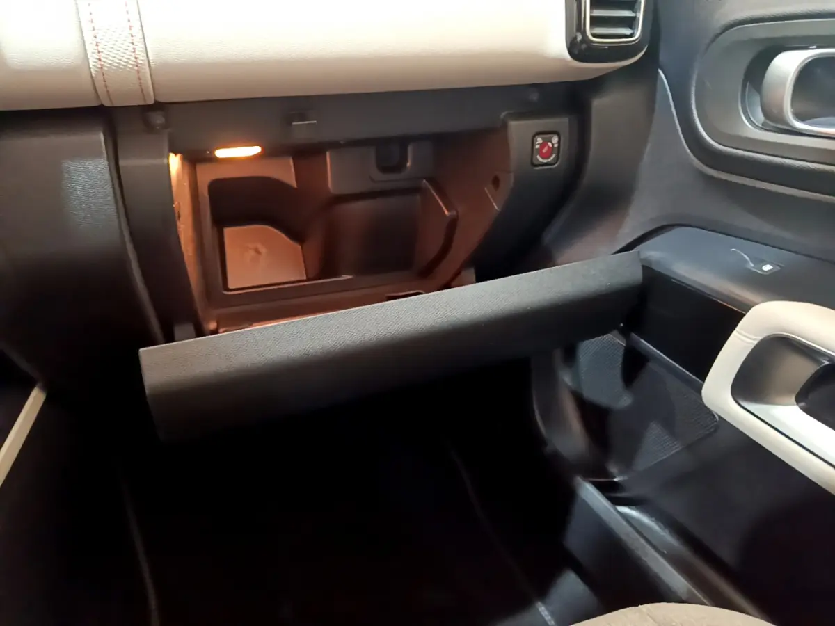 Vue intérieure côté passager du coffre à gants ouvert du Citroën C5 Aircross Hybrid 225 ë-EAT8 Shine, avec éclairage intérieur.