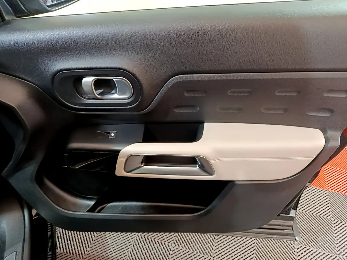 Gros plan sur la porte intérieure côté gauche du Citroën C5 Aircross Hybrid 225 ë-EAT8 Shine avec garniture noire et beige.