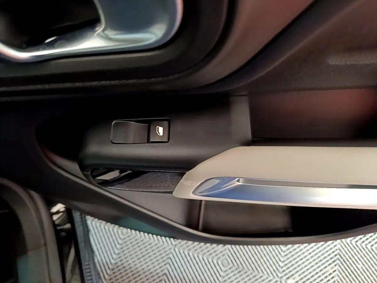 Détail de la commande de lève-vitre côté gauche sur la porte intérieure beige et noire du Citroën C5 Aircross Hybrid 225 ë-EAT8 Shine.