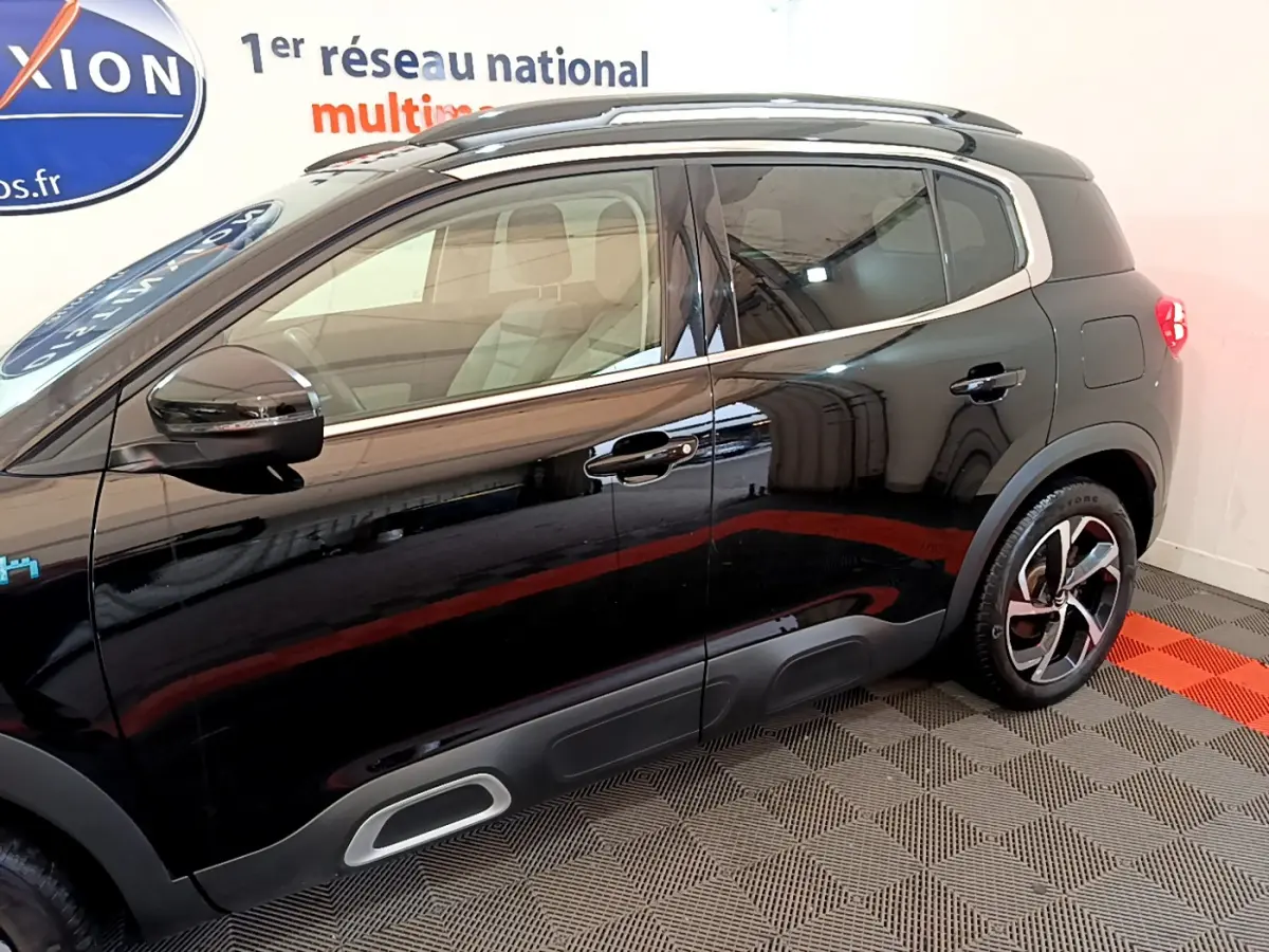 Profil côté gauche noir brillant du Citroën C5 Aircross Hybrid 225 ë-EAT8 Shine avec jantes alliage et protections basses grises.