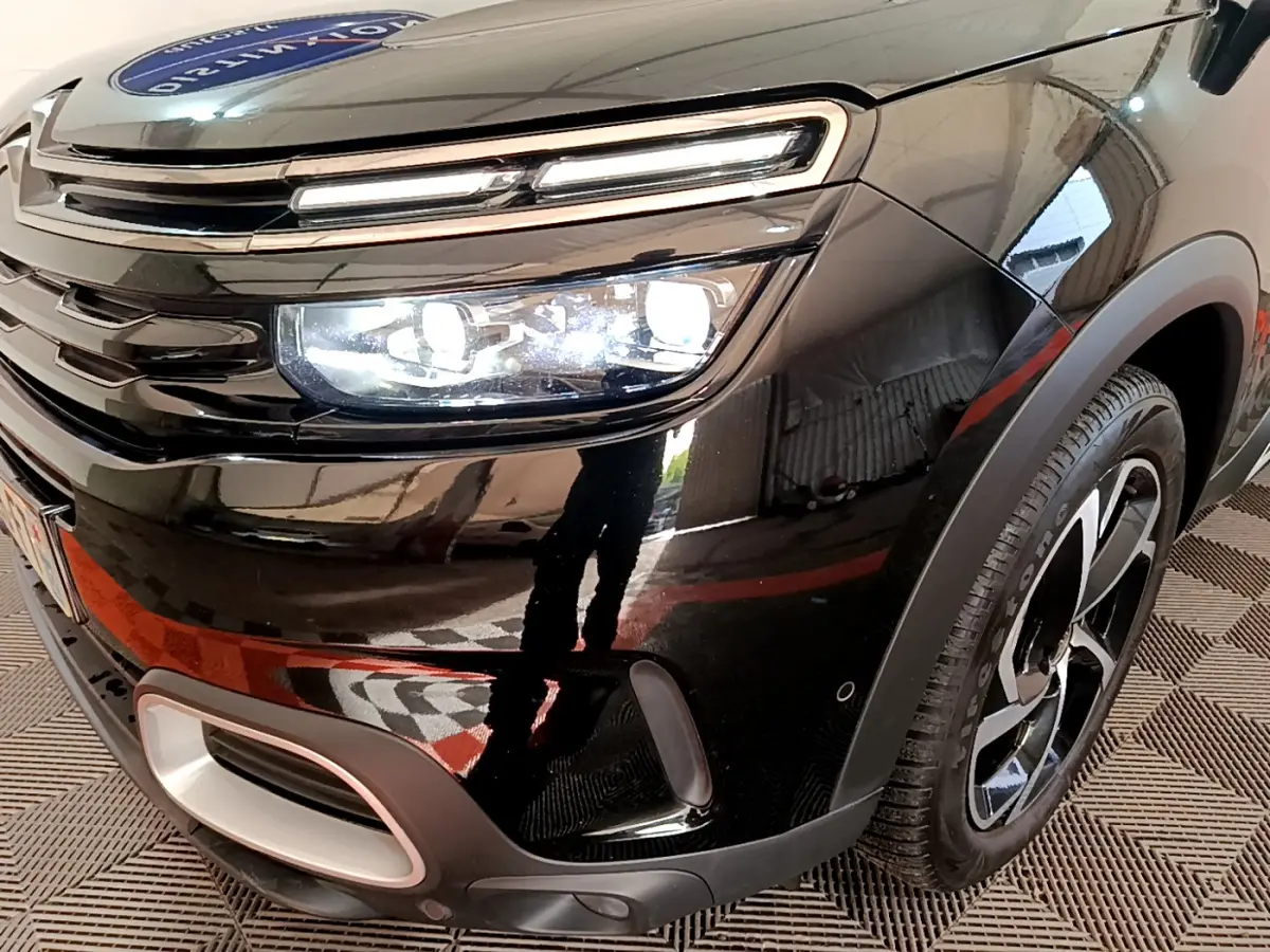 Gros plan sur l'avant droit noir du Citroën C5 Aircross Hybrid 225 ë-EAT8 avec phares LED allumés et jante stylisée.