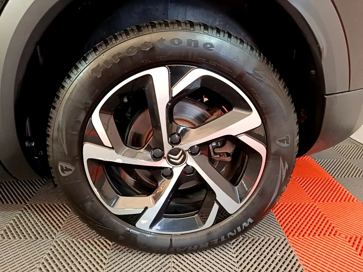 Gros plan sur la roue avant droite du Citroën C5 Aircross Hybrid 225 ë-EAT8 Shine noire avec jante alliage bicolore et pneu Firestone.