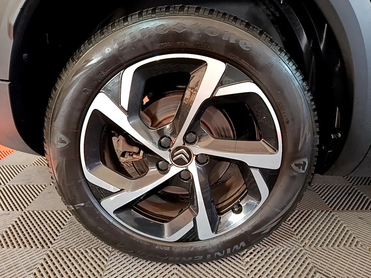 Gros plan sur la jante alliage bicolore et le pneu Firestone d'un Citroën C5 Aircross Hybrid noir, côté arrière.