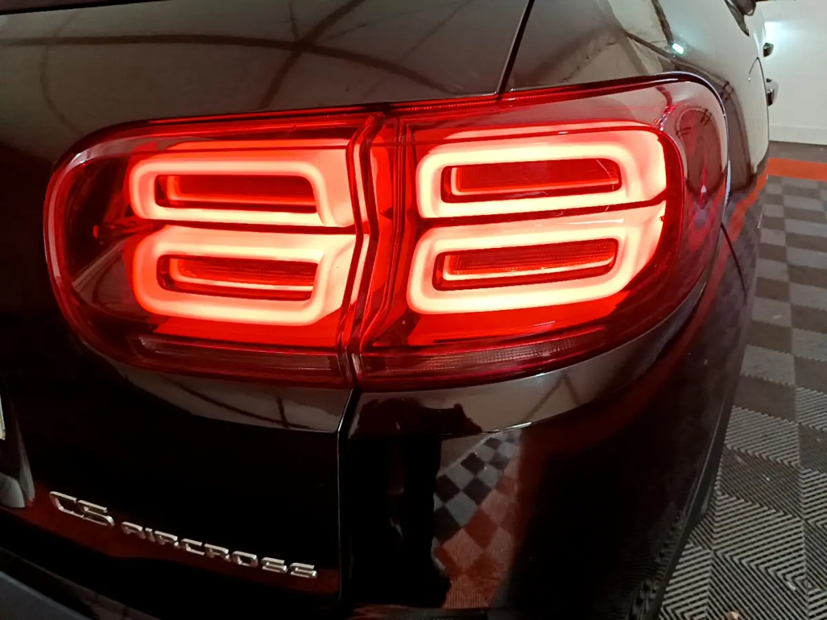 Feu arrière droit allumé du Citroën C5 Aircross Hybrid noir, vue rapprochée en intérieur.