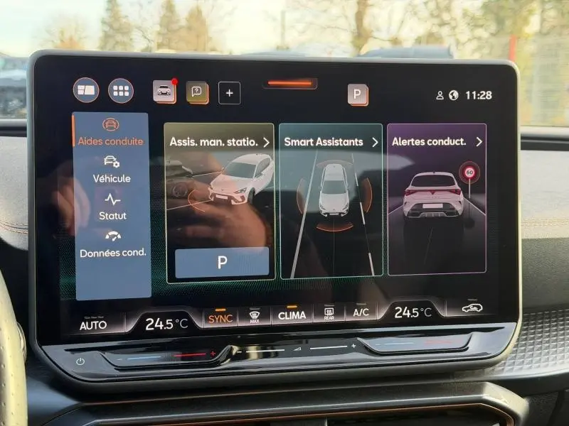 Écran tactile du système d’aide à la conduite de la SEAT LEON 2025, affichant les assistants de stationnement et alertes, intérieur noir.