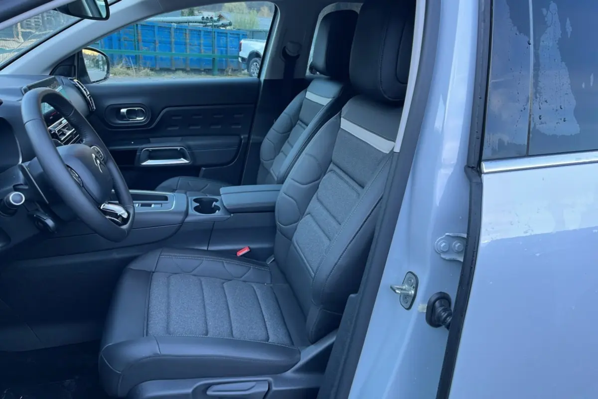 Vue intérieure côté conducteur du Citroën C5 Aircross blanc okénite, montrant les sièges avant en cuir et tissu gris.