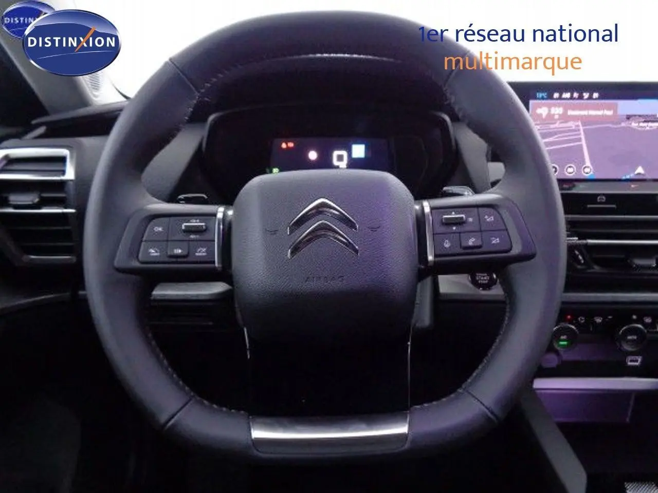 Volant en cuir noir avec logo Citroën au centre, tableau de bord numérique et écran tactile en arrière-plan.