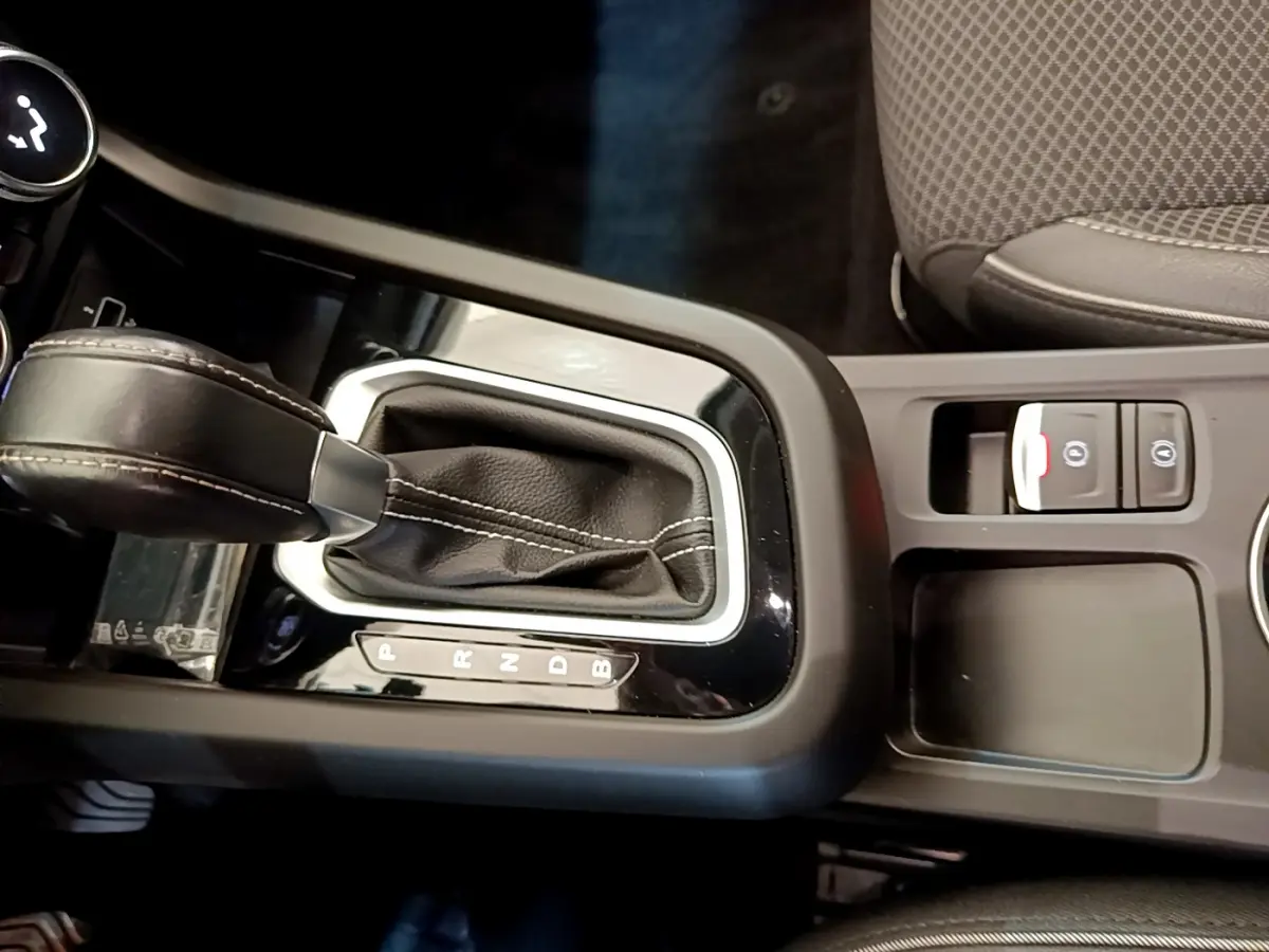 Gros plan sur la console centrale de la Renault Arkana Techno E-Tech 145 hybride, avec levier de vitesse cuir noir et boutons frein électrique.
