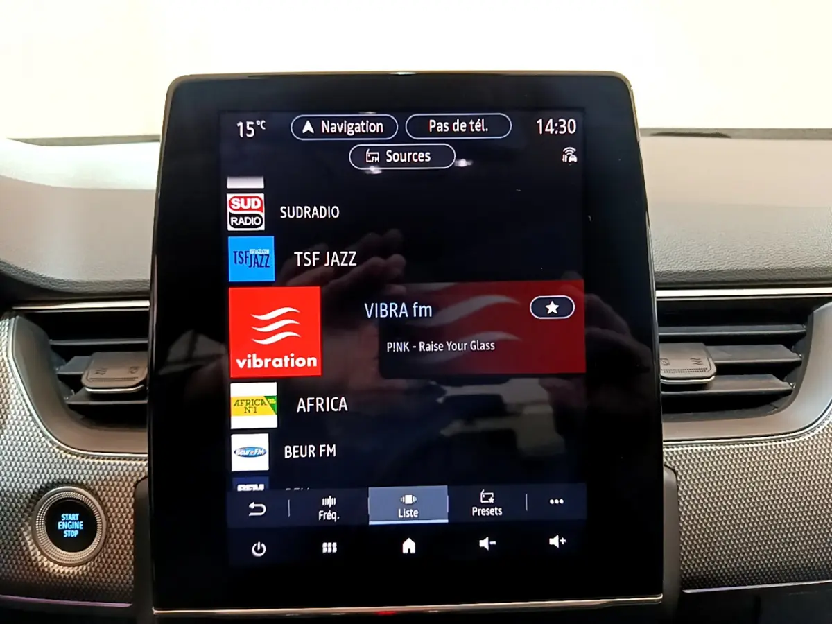 Écran tactile central de la Renault Arkana Techno E-Tech 145, affichant les stations radio, avec bouton démarrage visible à gauche.