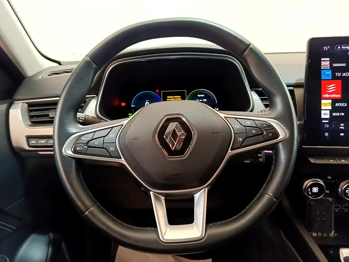 Vue intérieure centrée sur le volant noir de la Renault Arkana Techno E-Tech 145 avec tableau de bord numérique et écran tactile.