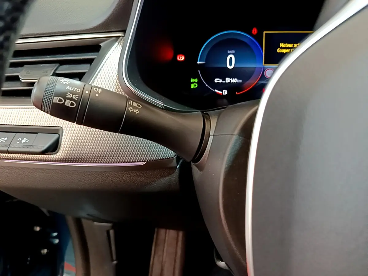 Gros plan sur le combiné d'instruments numérique bleu et le commodo des phares du tableau de bord du Renault Arkana Techno E-Tech 2023.