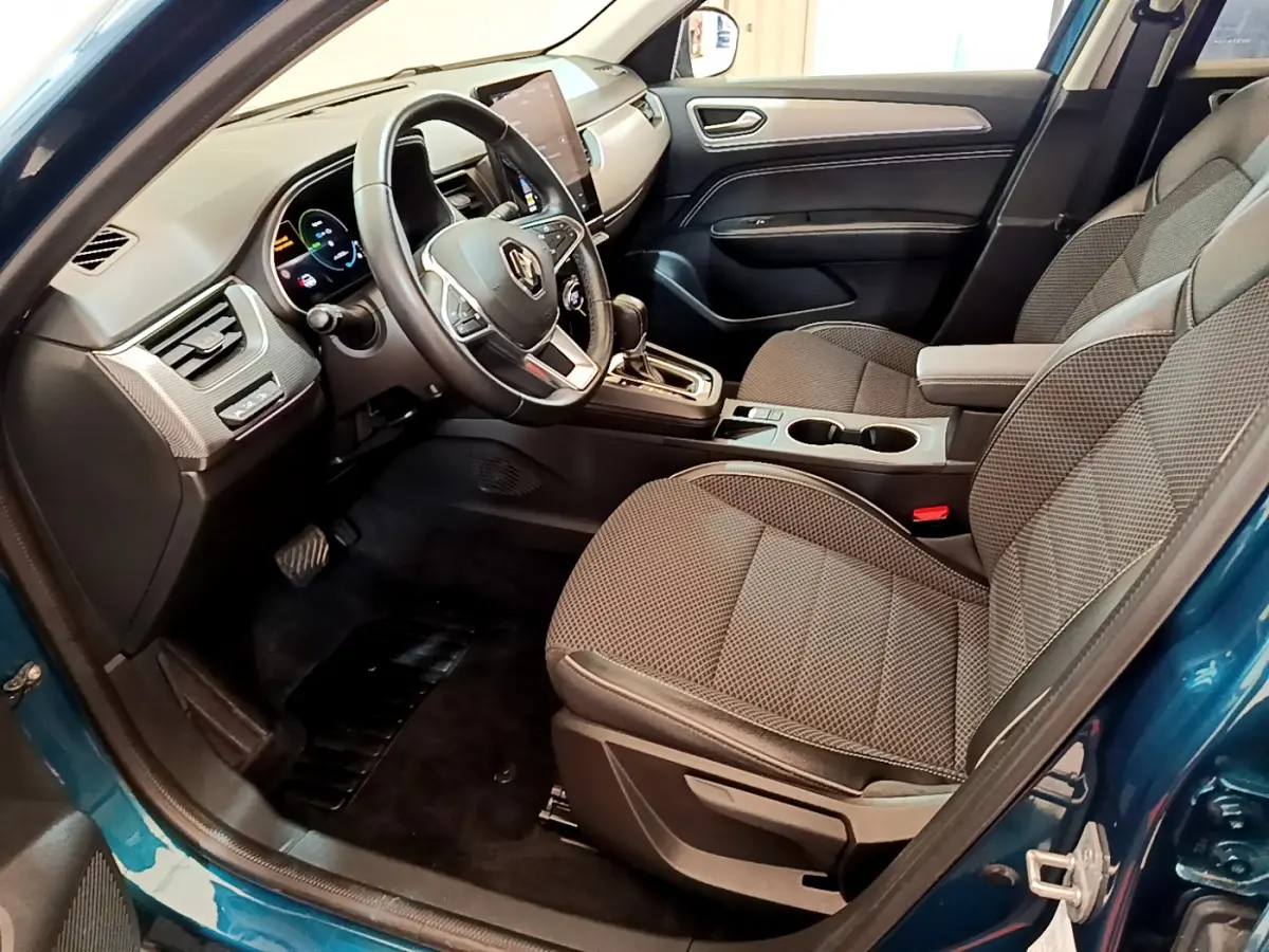 Vue intérieure côté conducteur de la Renault Arkana bleu 2023, avec tableau de bord numérique et sièges tissu gris.