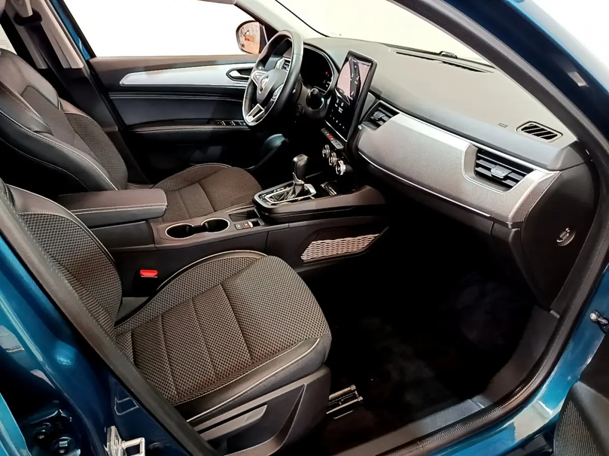 Vue intérieure côté conducteur de la Renault Arkana bleu 2023, avec tableau de bord moderne et écran tactile vertical.