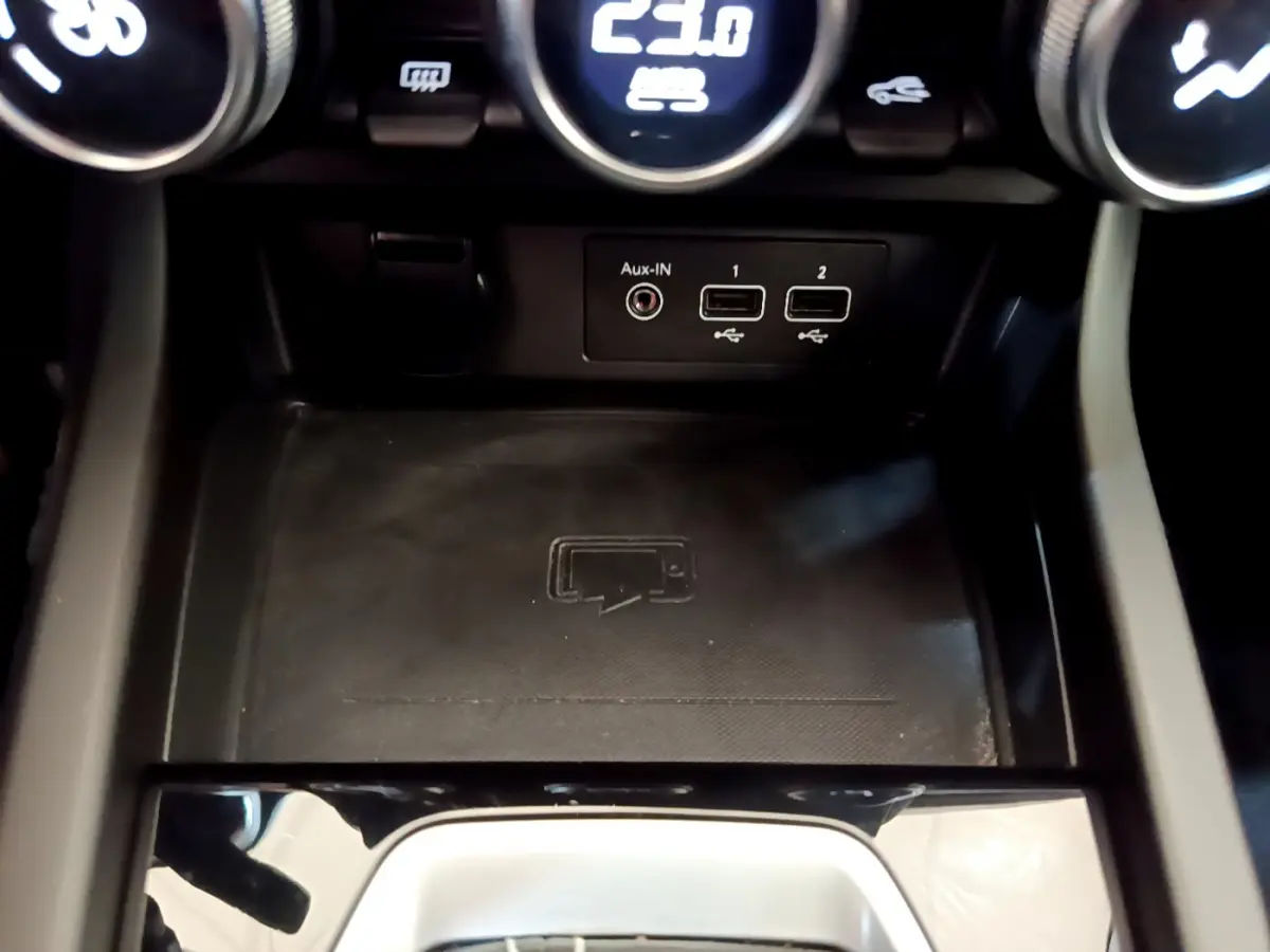 Gros plan sur la console centrale noire du Renault Arkana Techno E-Tech 2023 avec ports USB et zone de recharge sans fil.