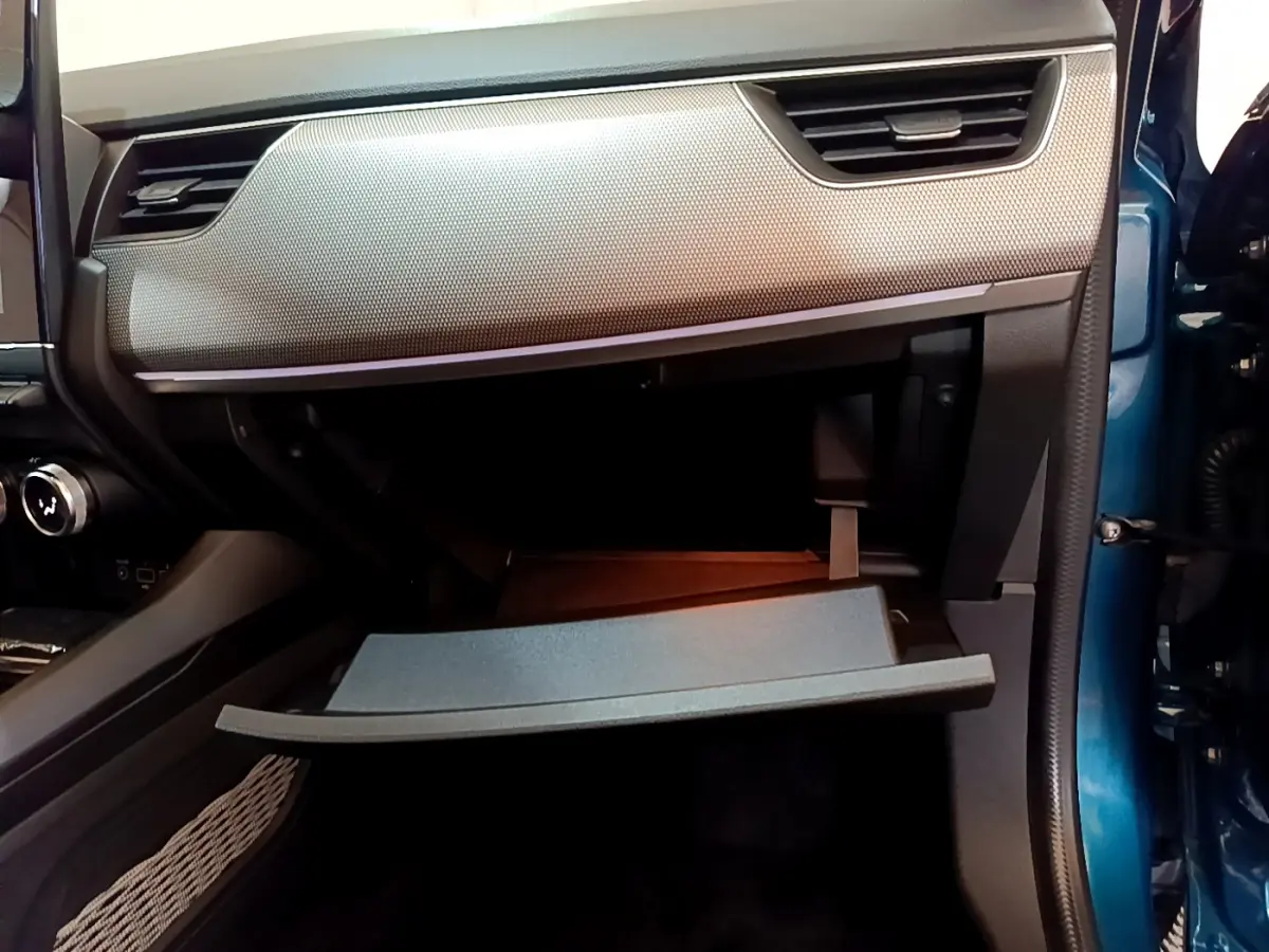 Vue intérieure côté passager du coffre à gants ouvert d’un Renault Arkana bleu, soulignant la finition moderne du tableau de bord.