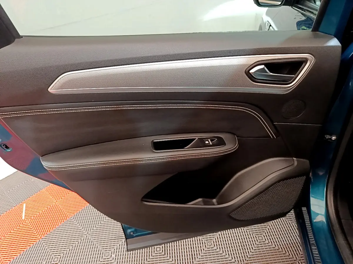 Vue intérieure côté gauche de la porte avant d’un Renault Arkana bleu, avec garniture noire et insert argenté.