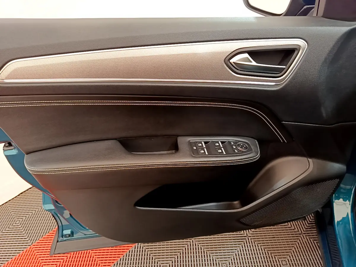 Vue côté gauche de la porte avant bleu Renault Arkana 2023 avec garniture noire, surpiqûres et commandes électriques.
