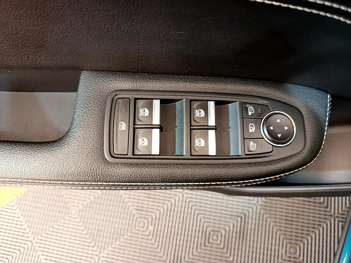 Gros plan sur les commandes de lève-vitres et rétroviseurs sur la porte côté conducteur du Renault Arkana bleu 2023.