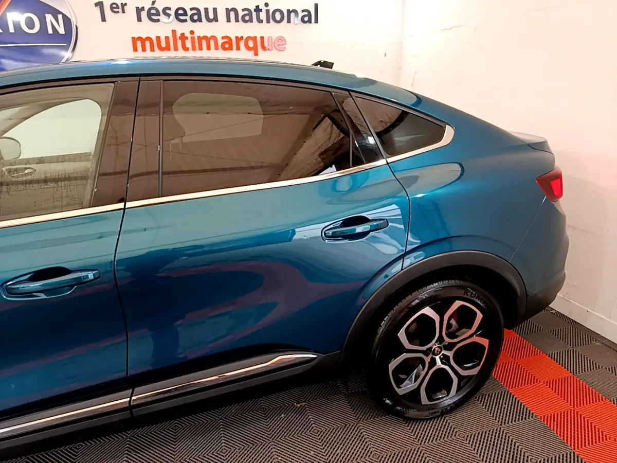 Vue latérale droite du Renault Arkana bleu 2023, mettant en valeur la ligne fluide et les poignées de porte intégrées.