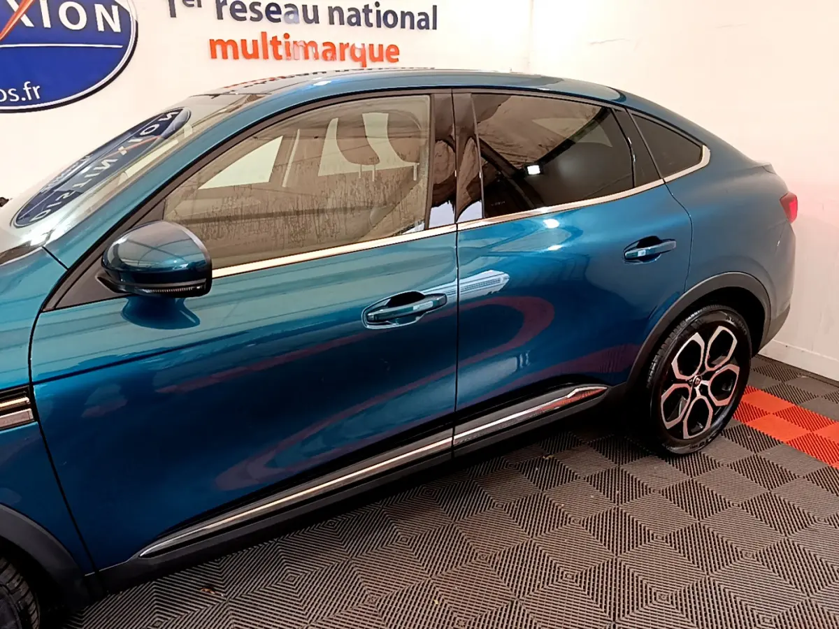 Vue latérale droite d’un Renault Arkana bleu 2023 avec jantes distinctives et vitres teintées.