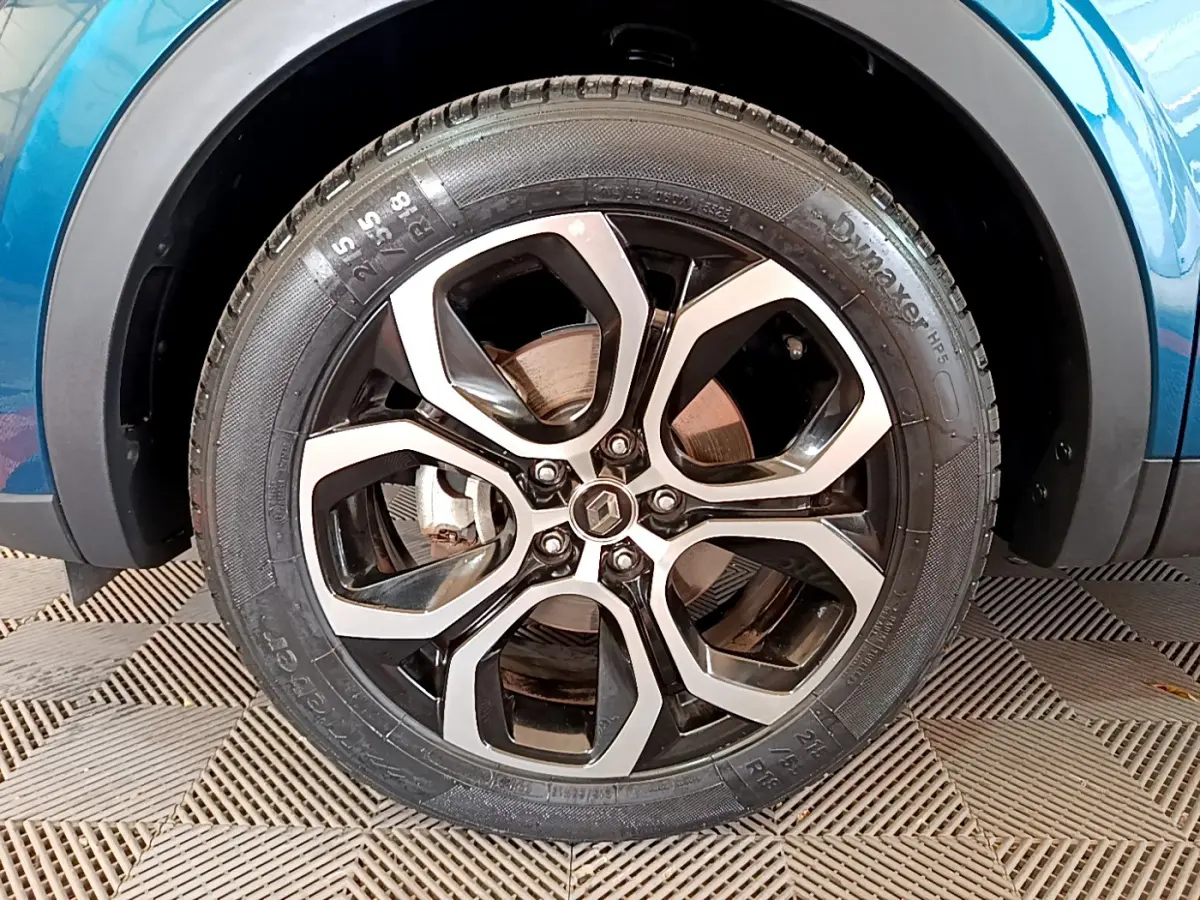 Gros plan sur la roue avant droite du Renault Arkana bleu 2023 avec jante alliage bicolore et logo Renault central.