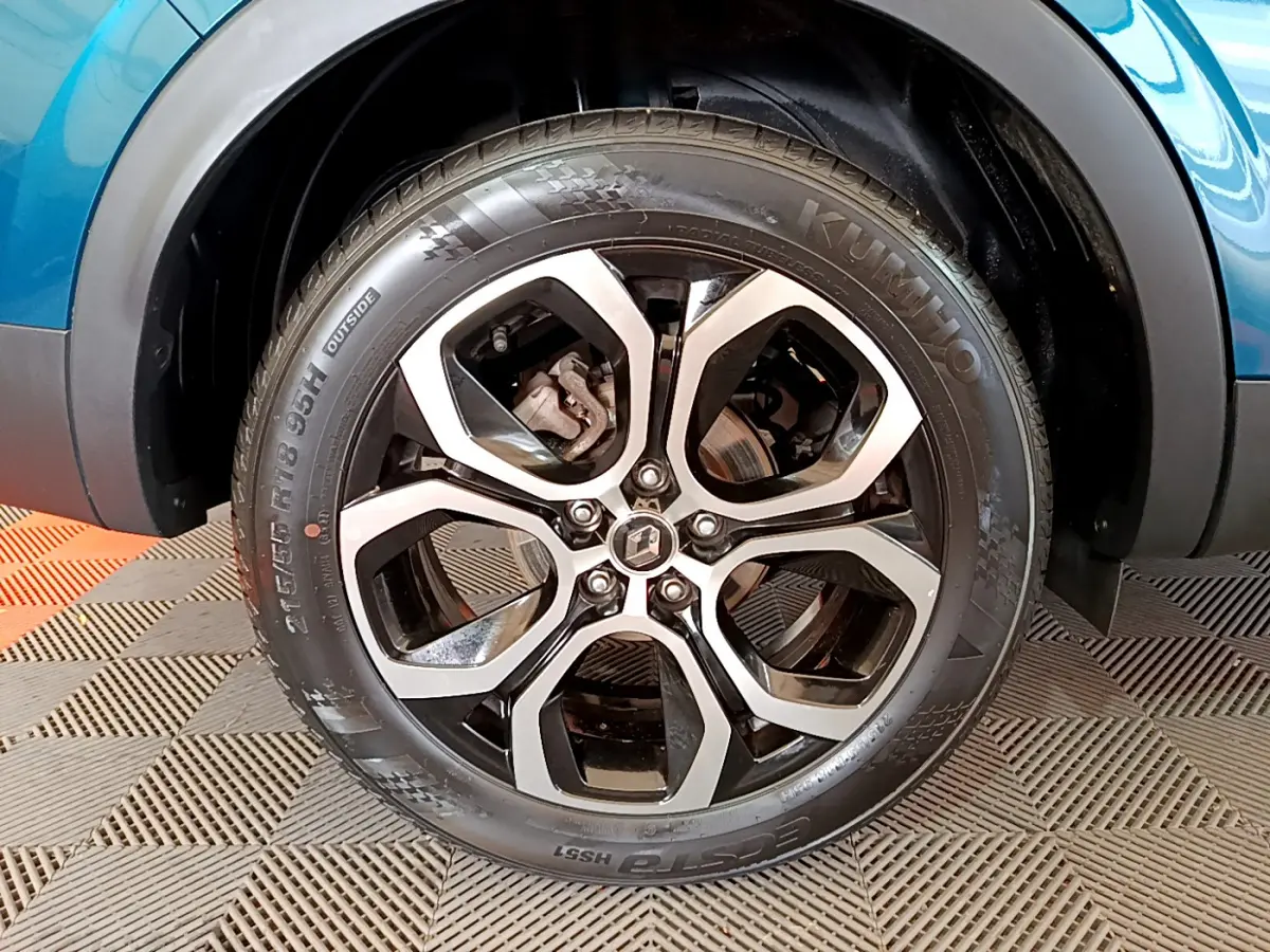 Gros plan sur la roue avant droite du Renault Arkana bleu 2023 avec jante alliage noire et argentée.