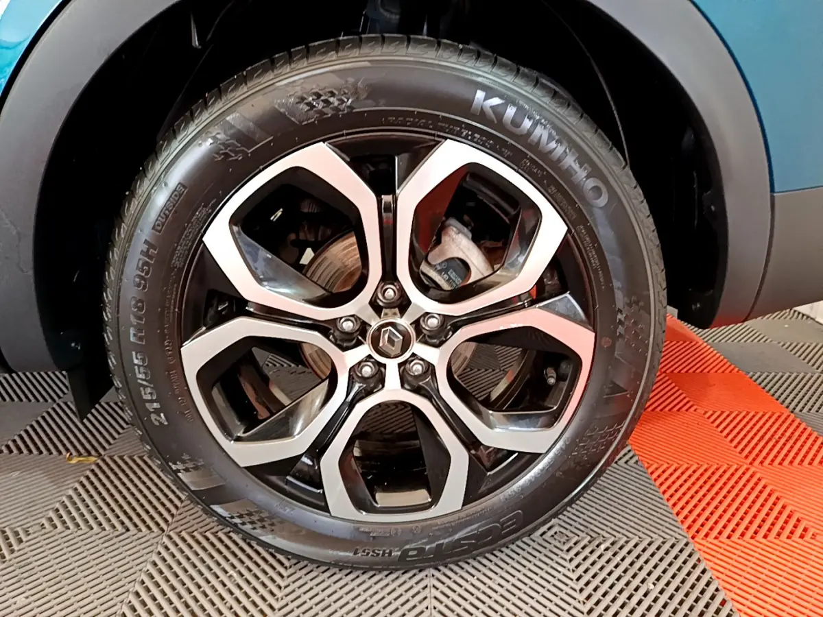 Gros plan sur la roue avant gauche du Renault Arkana bleu, mettant en valeur la jante alliage noire et argentée.