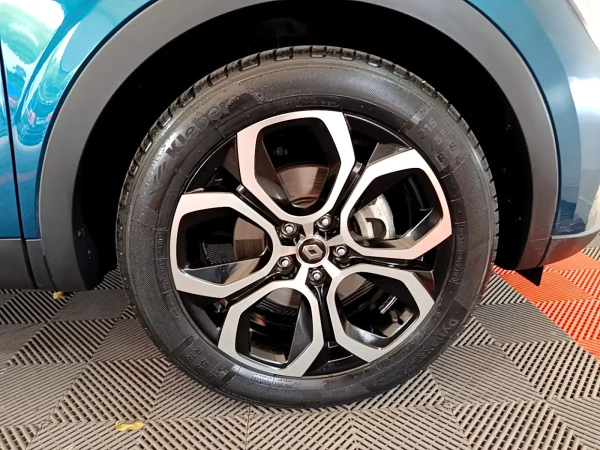 Gros plan sur la roue avant droite d’un Renault Arkana bleu, mettant en valeur la jante alliage moderne.