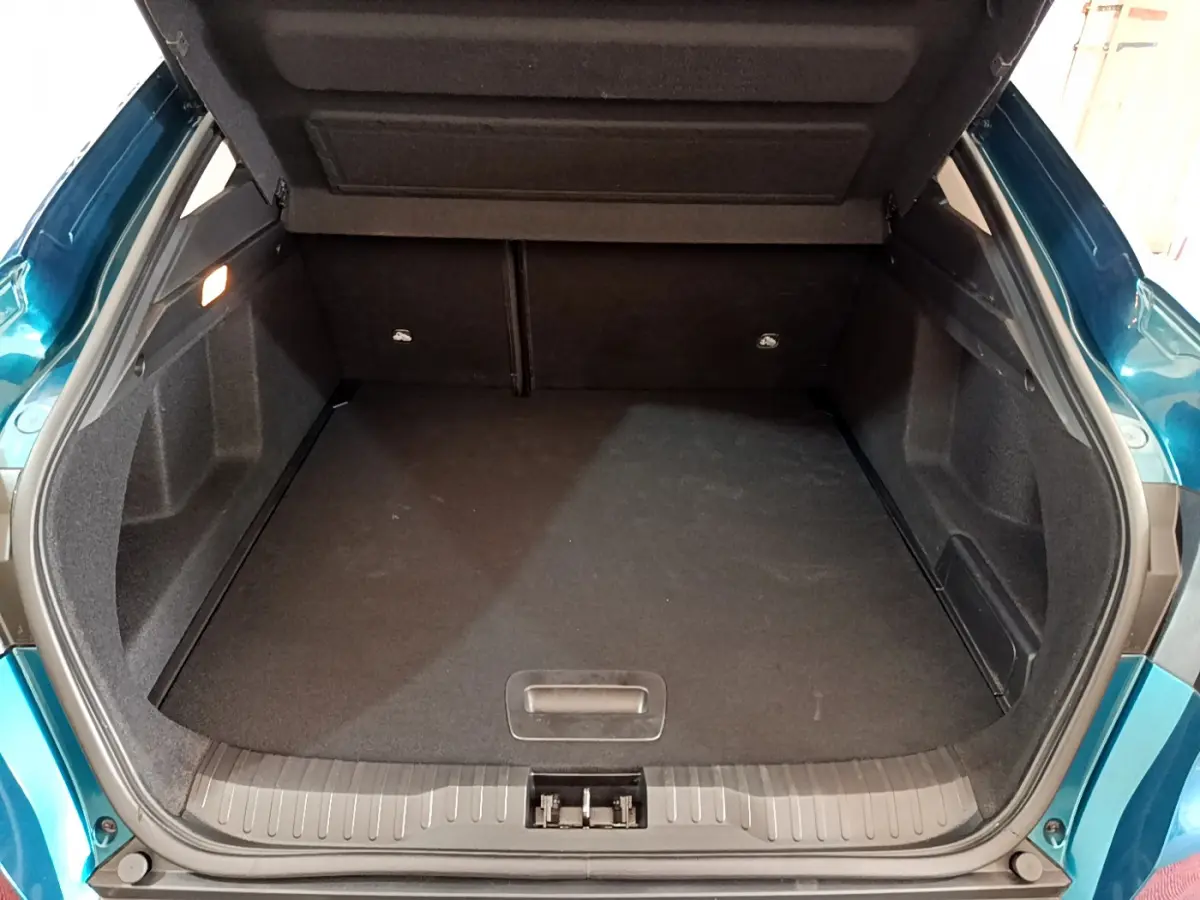 Coffre ouvert vu de l'arrière d'un Renault Arkana bleu, montrant un espace de chargement spacieux et propre.