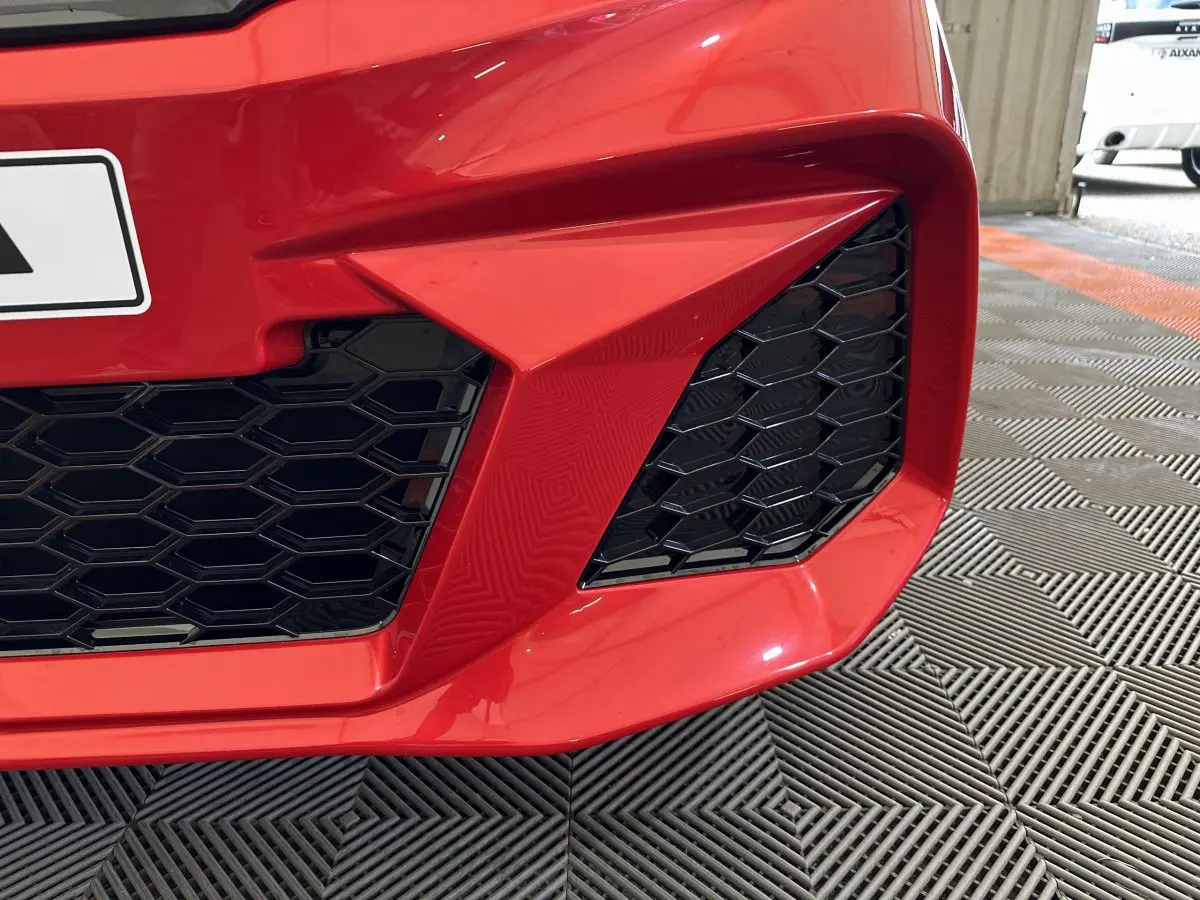 Gros plan sur la calandre avant rouge de l'AIXAM AMBITION 0.5 CITY COUPE GTI E5+ avec grille noire hexagonale.